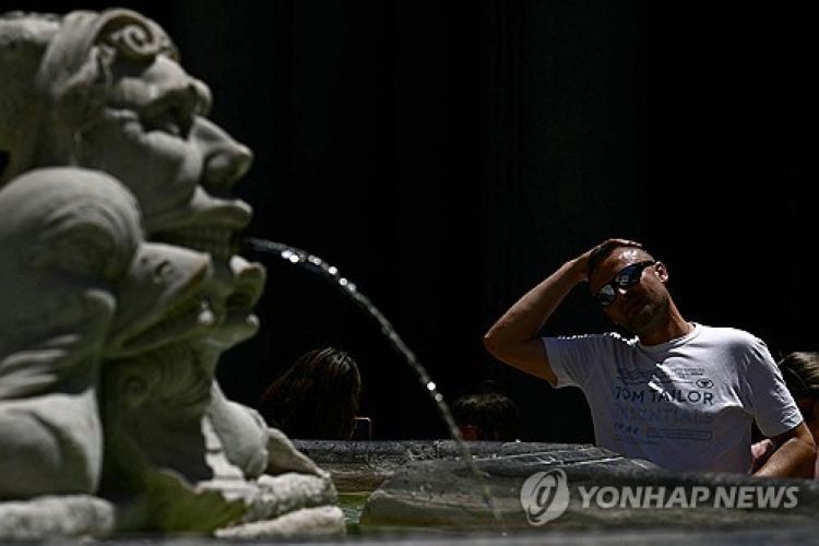 이탈리아 로마의 한 분수대에서 물로 머리를 식히는 관광객