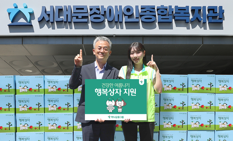 하나금융그룹 직원이 송용성 서대문장애인종합복지관장(왼쪽)에게 행복상자를 전달한 후 기념촬영을 하고 있다.(사진=하나금융그룹)